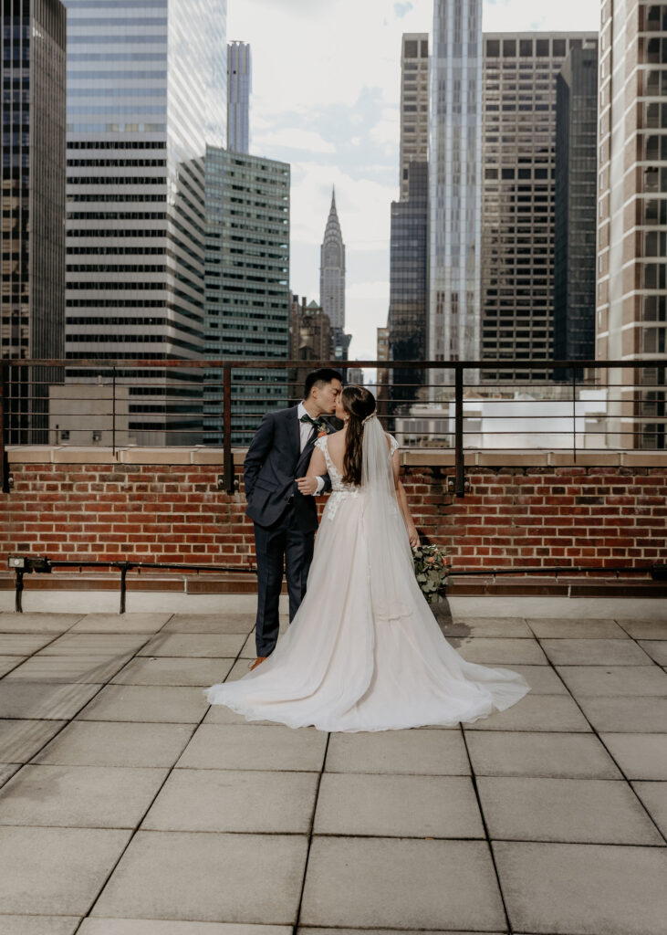 Beautiful Bride and groom kissing on Tribeca Rooftop with New York Skyline in the background