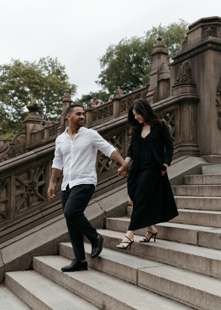 playful NYC engagement photo on the stairs with sleek black dress and classy casual vibes