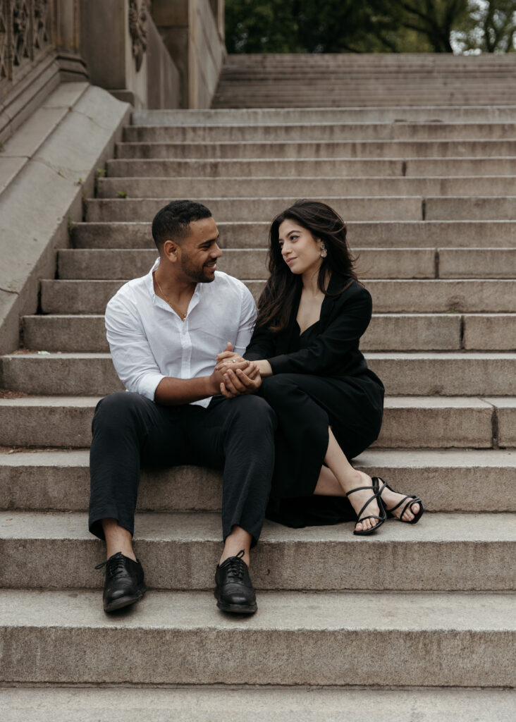 elegant NYC engagement photo on the stairs with sleek black dress and classy casual vibes