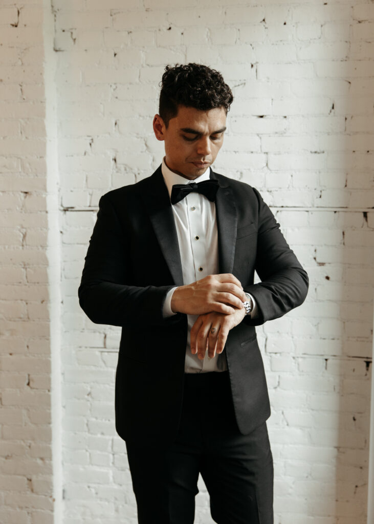 groom getting ready in Ace hotel, white brick wall in the backdrop