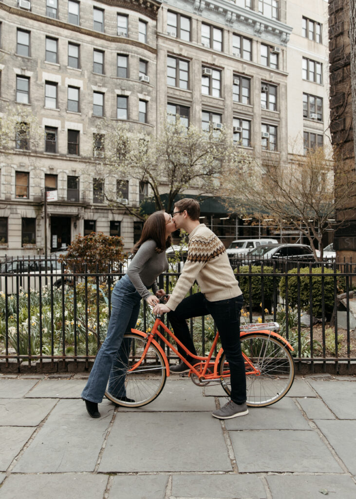 Romantic and playful couple riding a bike together for their engagement photos in NYC